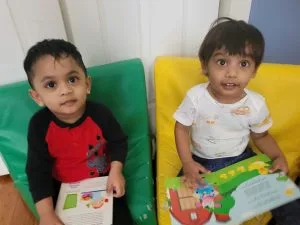 Two toddlers holding picture books in the reading corner