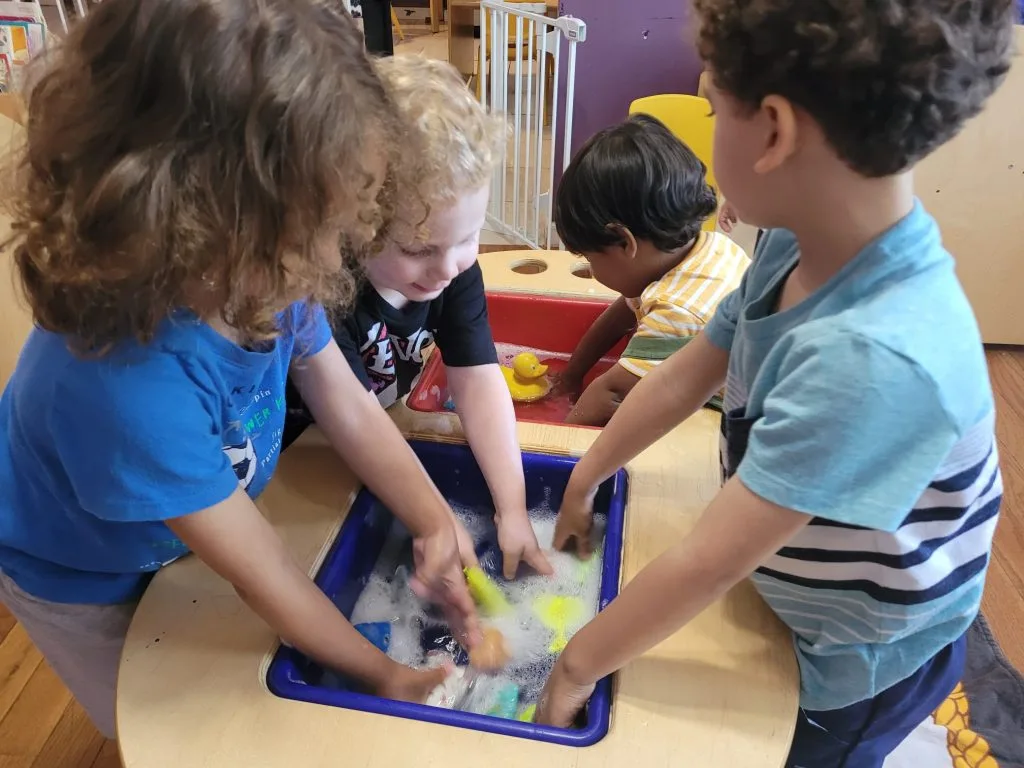 Children playing together at the sensory table at Rainbow Palace