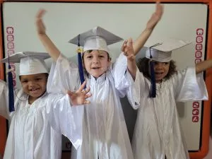 Rainbow Palace preschool graduates celebrating in white caps and gowns